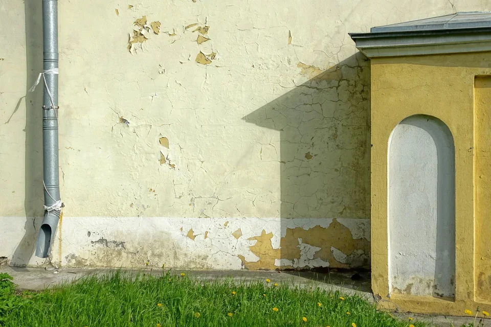 Mur enduit dont la peinture s'écaille, avec une descente d'eau